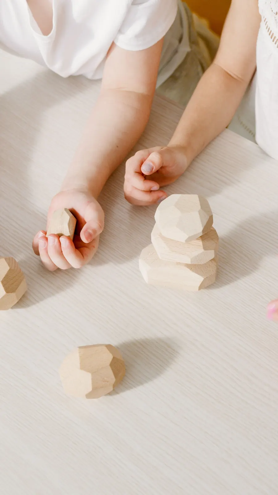 A young child's hands stacking natural wooden blocks on a table