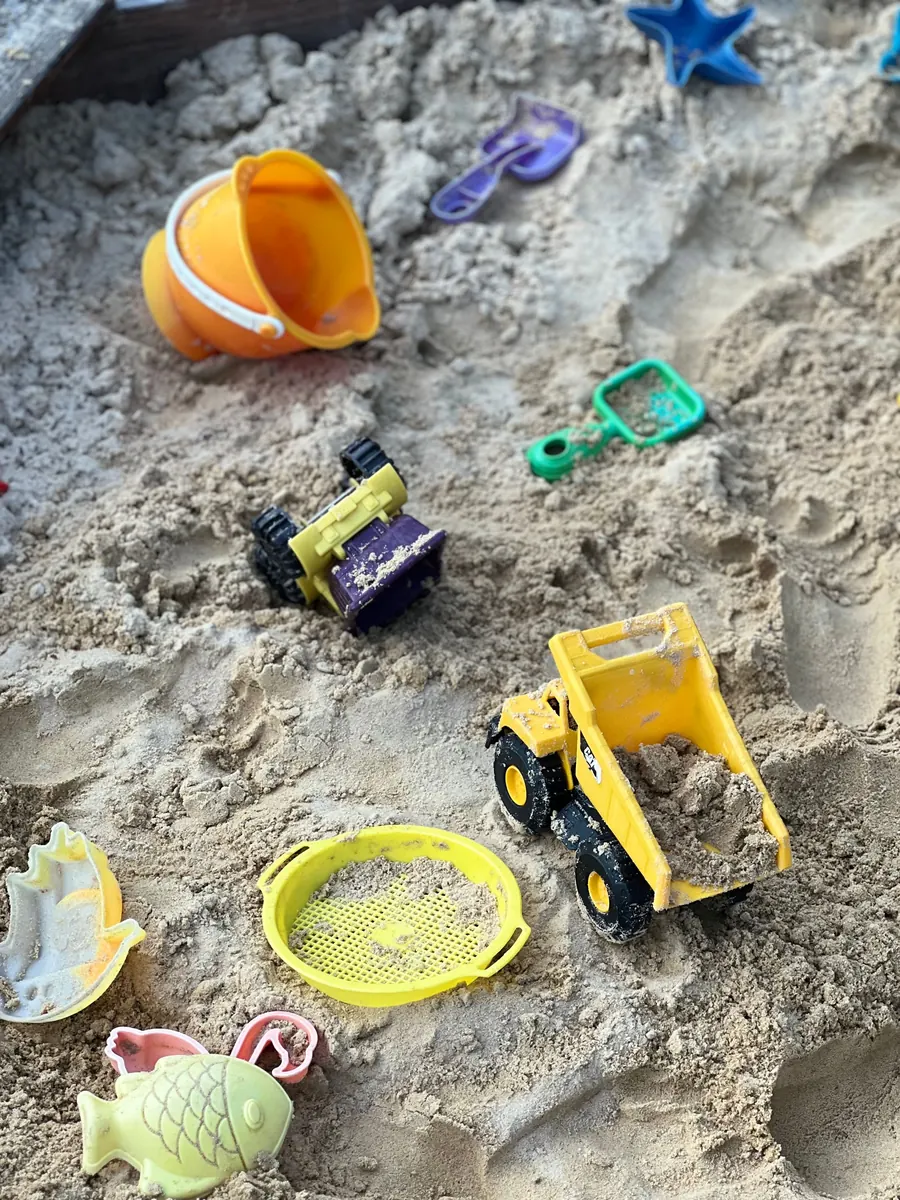Toy trucks, shovels and sand molds in a sandbox